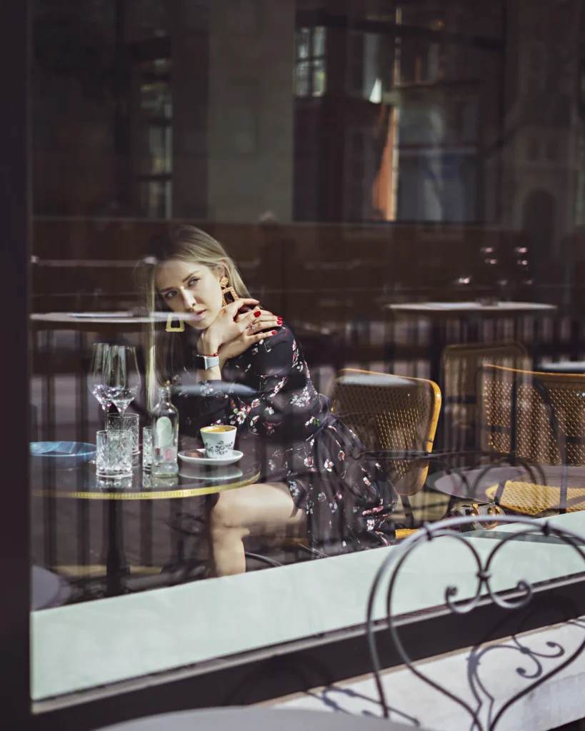 artistic portrait photography of a woman made through the shop window in the city with retro photography lens
