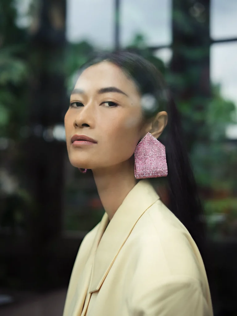 artistic portrait photography of a woman made through the shop window in the city with retro photography lens