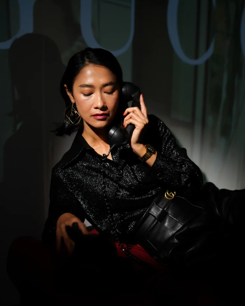 artistic portrait photography of a woman in a gucci dress with dynamic light in black colours and black retro telephone