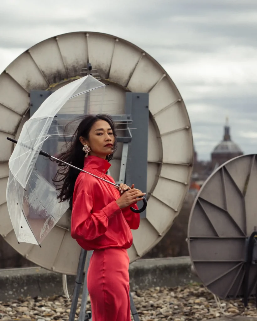 artistic portrait photography of a woman in a red dress with umbrella on the roof of the building