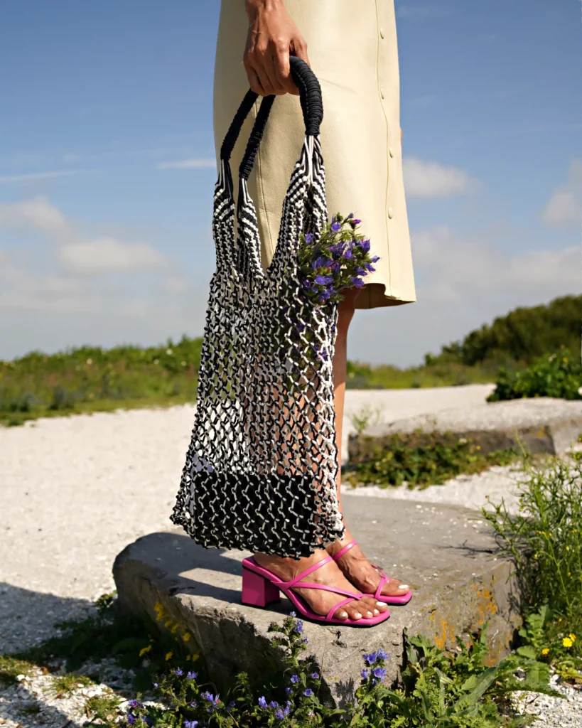 creative outside photography of an bag and pink sandals. bright outside theme, flowers