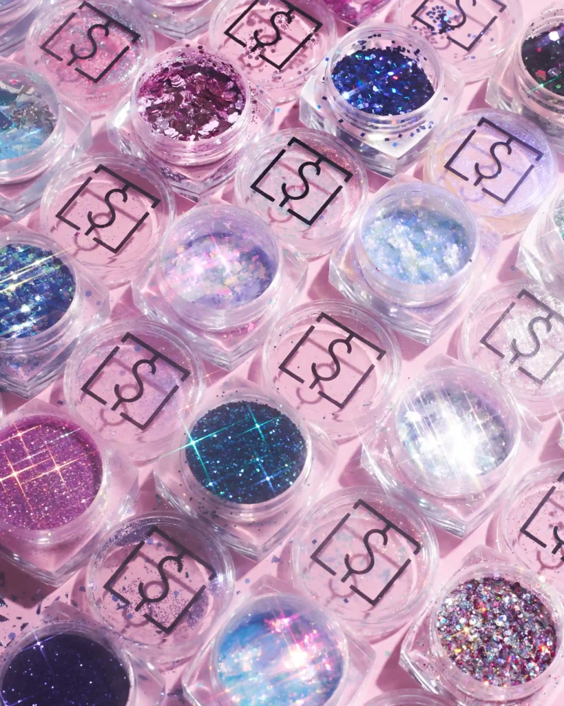 creative still life close up photography of nail glitter on the pink background with sparkles