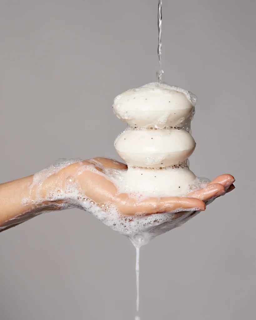 creative product advertising photo with a wet soapy hands holding a a soap and water dripping on it
