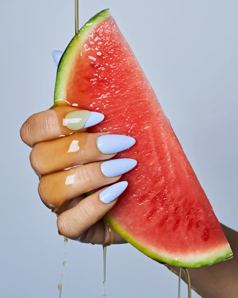 creative still life photography of a hand with blue nails holding a watermelon