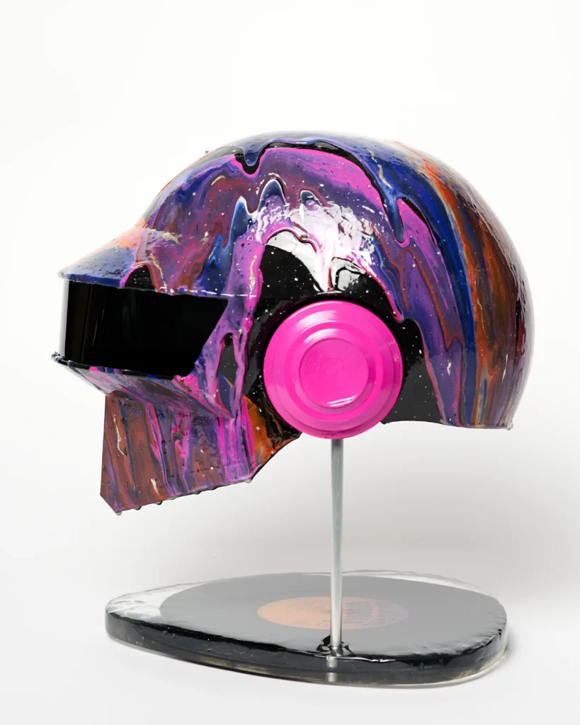 colourful galaxy painting on the art piece replica of a daft punk helmet. Full photo of a side on a stand.