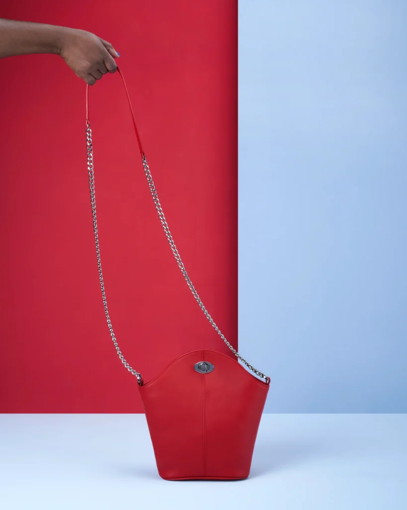 still life Packshot product photography of a red bag on a blue background with a hand