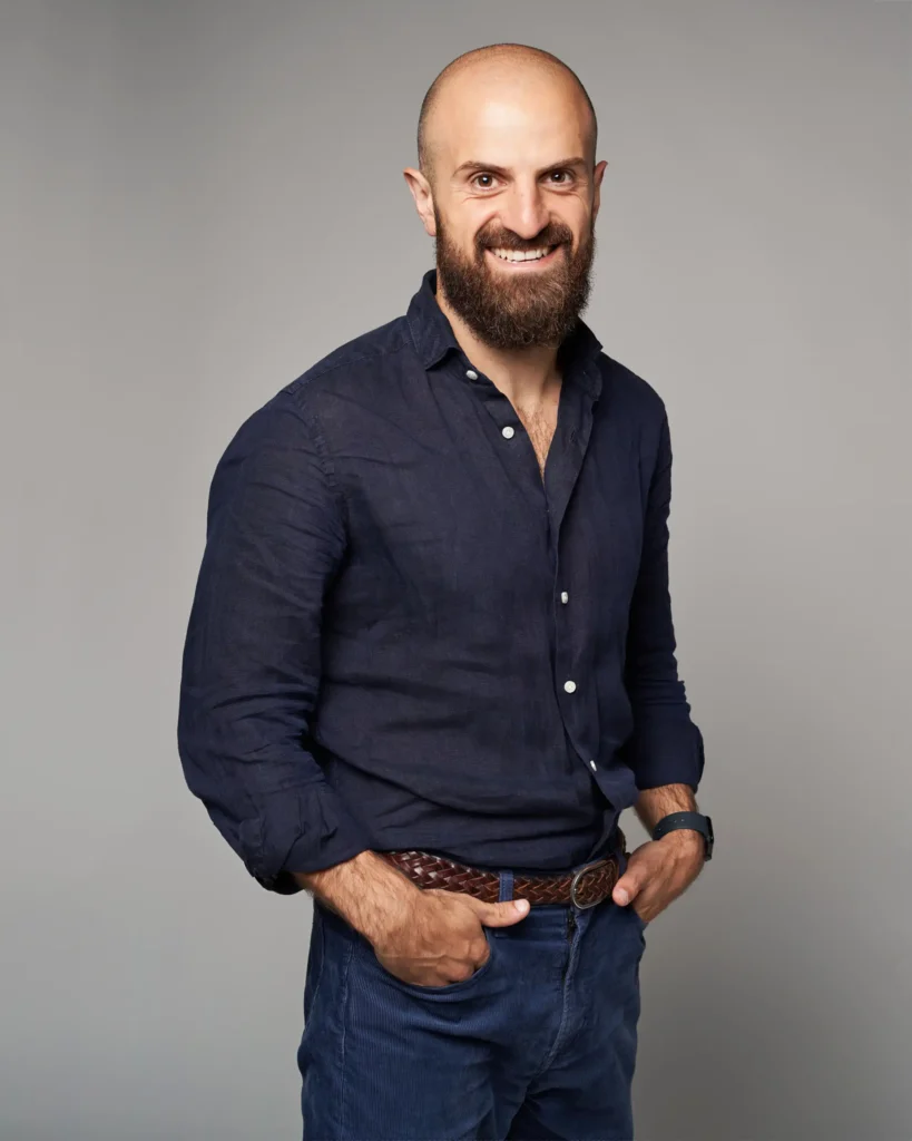 studio photography of a man on the grey background in a blue shirt with a smile made for Linked in page