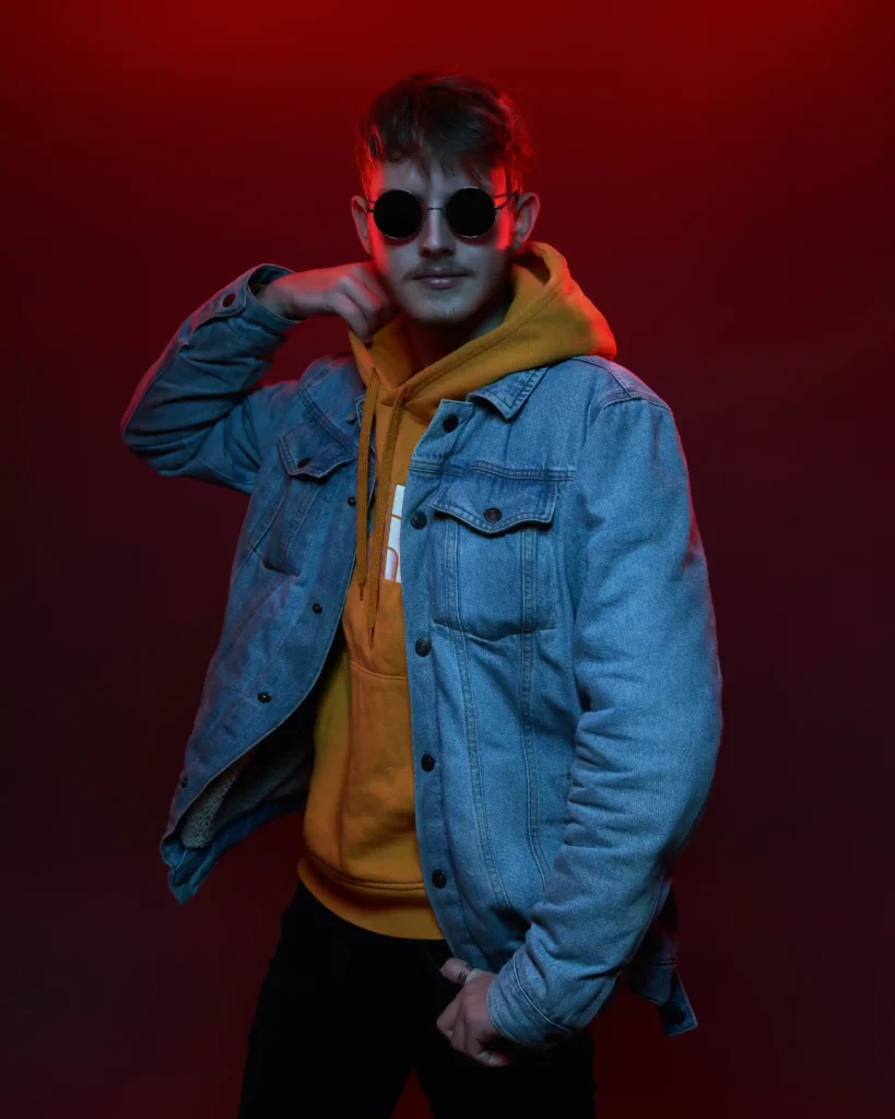 studio fotografie of a man in a red lights and yellow hoodie and a glasses