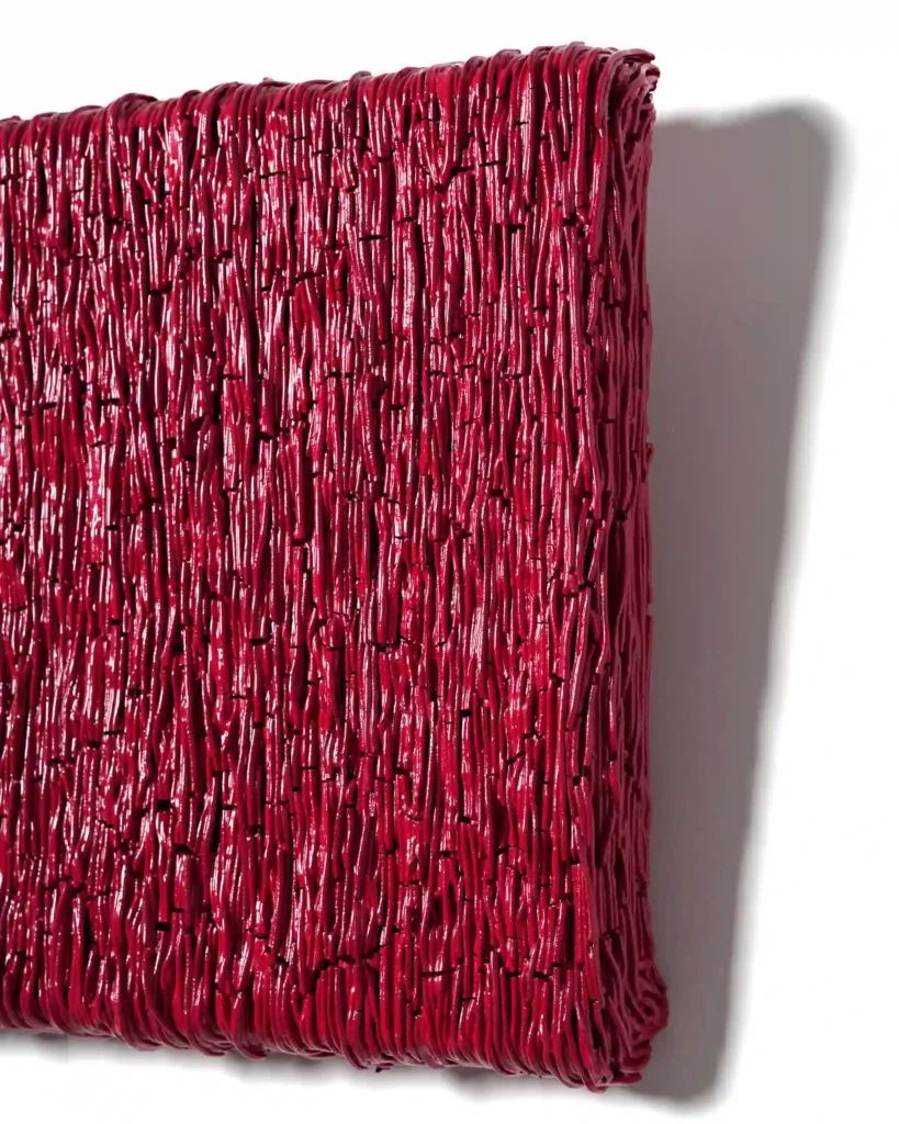 painting sculpture on the wall, thin lines of the red and pink plaster art. The view from the side